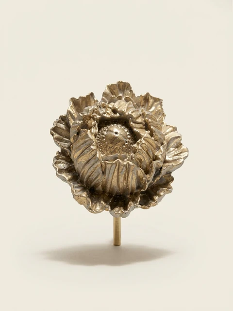 Gold decorative flower on a stake with layered, wavy petals and a rounded, patterned centre.