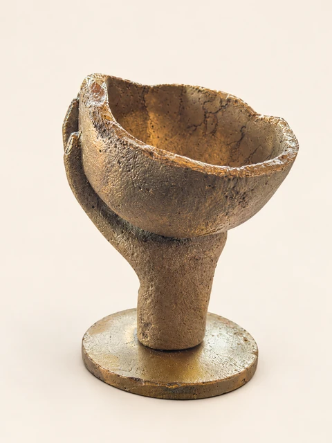 Bronze bowl with an irregular rim, on a hand form and a round foot