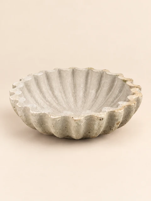 Small, shallow light bowl with fine ribs, a thin wavy rim and an uneven texture