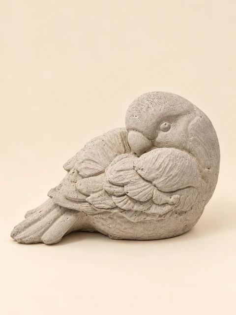 Bird in concrete colour with a curved neck, its head against its wing and a raised feather pattern
