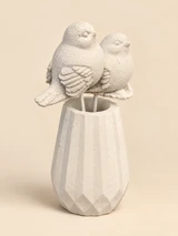 Two light birds on slender stakes in a light, angular vase, seen from the front