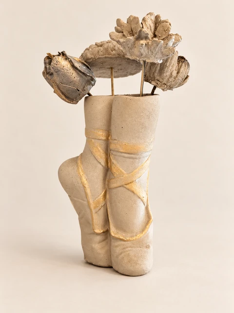 Light ballet shoe vase with gold ribbons and four different flower forms on slender stems. Main view.