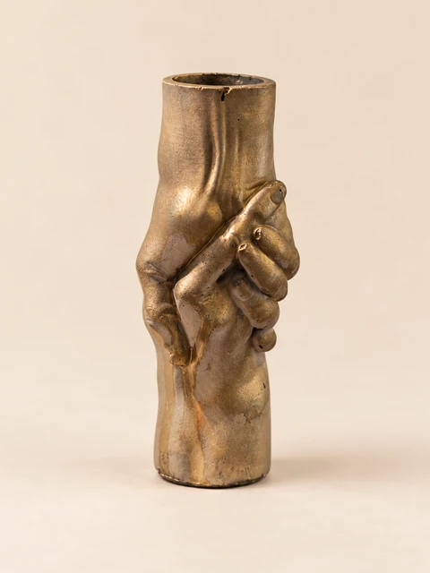 Small cylindrical vase in gold and grey tones with hand forms at the front