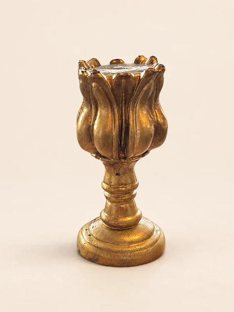 Gold candle holder with a petal pattern, a smooth top surface, a slender stem and a stepped foot