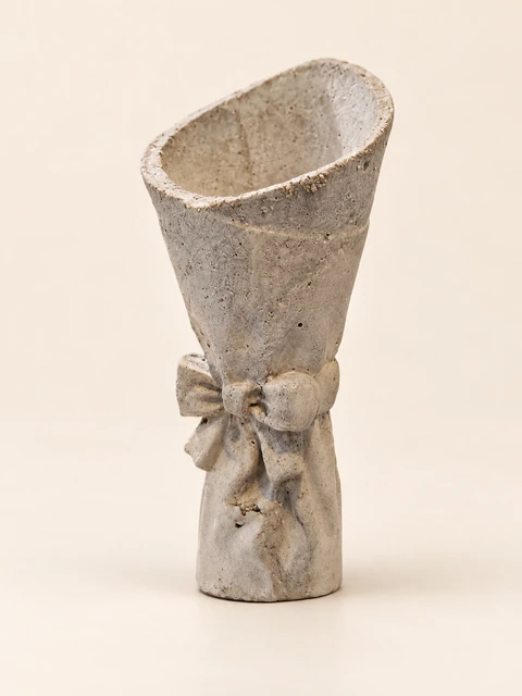 Small grey vase with a slanted upper rim, a raised bow and a rough surface