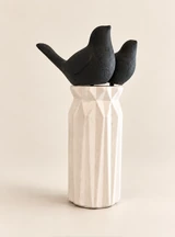 Two matte black birds with simple forms and upturned tails in a tall, white vase. Main view.