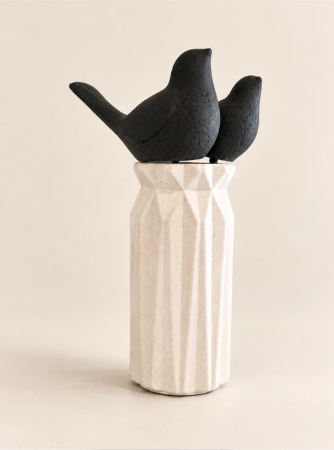 Two matte black birds with simple forms and upturned tails in a tall, white vase. Main view.