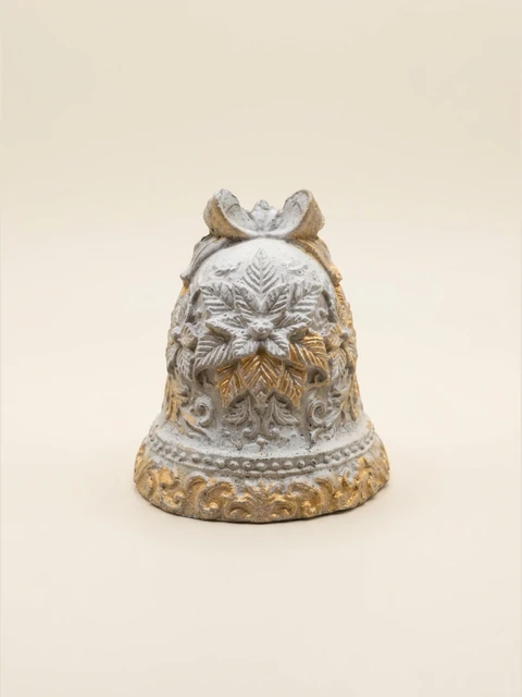Light Christmas bell with a bow, raised flower and leaf patterns and gold accents on the leaves and lower rim. Visible grey concrete texture.