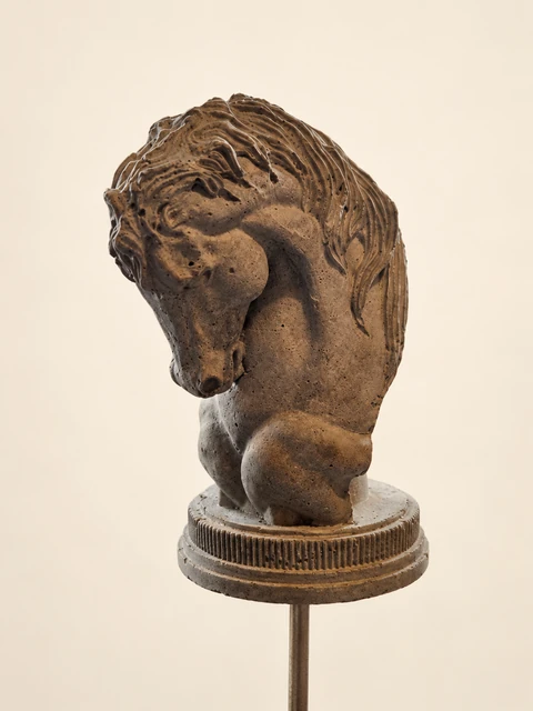 Horse head with a prominent mane on a round, ribbed pedestal and a slender stake