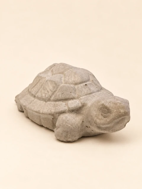 Turtle in concrete colour with a low patterned shell, a rounded head and short legs
