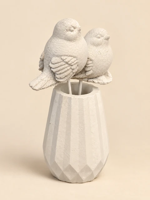 Two light birds on slender stakes in a light, angular vase, seen from the front