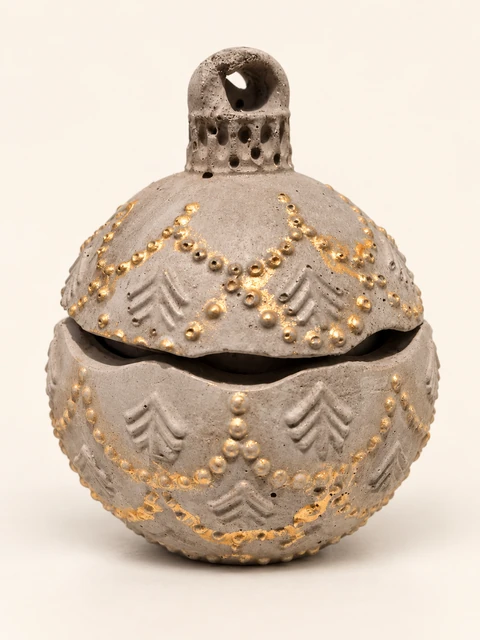 Spherical decorative container of grey concrete with a lid, a loop, raised fir trees and gold bead garlands