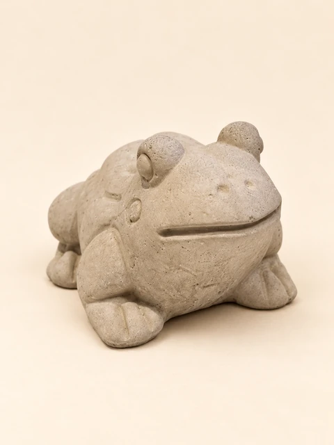 Single frog in concrete colour with a rounded body, raised eyes, a wide smiling mouth and shaped toes