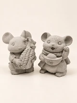 The same two mouse figures in concrete colour from another angle, with the corn cob on the left and the bowl form on the right